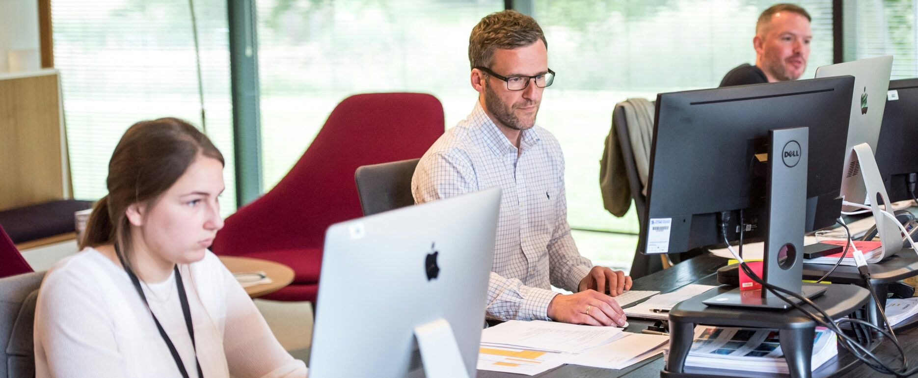 three people working on desktops, concentrating